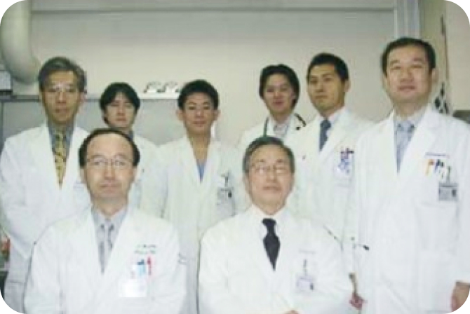 白衣を着た複数の医師が室内で整列し、正面を向いて撮影された集合写真